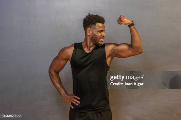 man biceps muscles in front of wall - flexionar los músculos fotografías e imágenes de stock