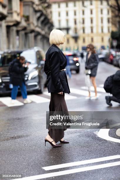 Cristina Musacchio is seen wearing a black blazer, a pink belt embellished with a 3d fabric flower, a brown long skirt and brown leather heeled...