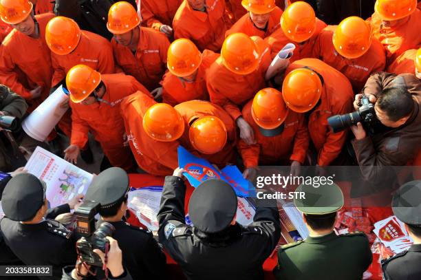 Chinese police hand out fire safety flyers on setting off fireworks during the lunar new year to construction workers in Beijing on February 2, 2010....