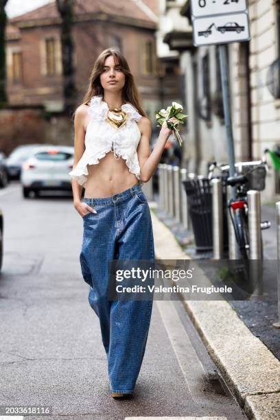 Mara Lafontan is seen wearing a huge pendant heart-shaped gold necklace, low waist, wide leg paillettes jeans, gold heeled sandals and a white...