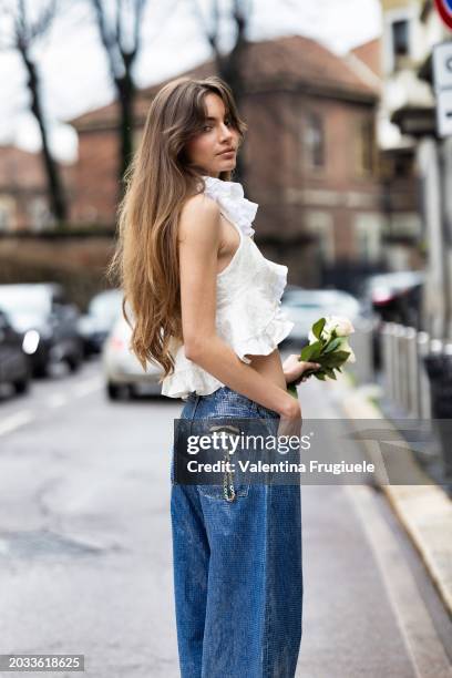 Mara Lafontan is seen wearing a huge pendant heart-shaped gold necklace, low waist, wide leg paillettes jeans and a white cropped top with rushes...