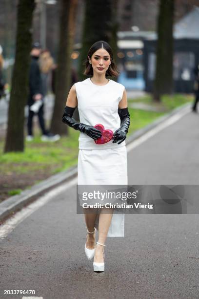 Heart Evangelista wears white sleeveless top, skirt, black gloves, heart shaped bag, platform shoes outside Sportmax during the Milan Fashion Week -...