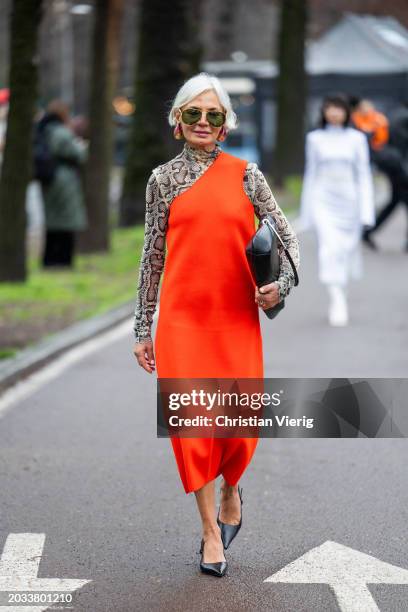 Grece Ghanem wears snake print long shirt, orange asymmetric dress, black bag outside Sportmax during the Milan Fashion Week - Womenswear Fall/Winter...