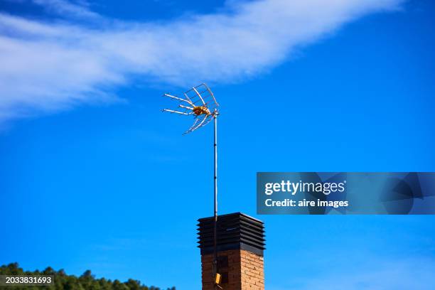 front view of a chimney on the roof of a house with a tv antenna, blue sky in the background. - new broadcasting house stock pictures, royalty-free photos & images