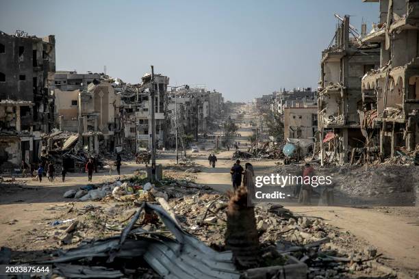 Palestinians walk past buildings destroyed during Israeli strikes in Beit Lahia in northern Gaza, on February 26 amid continuing battles between...