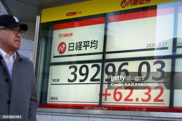 Man walks past an electronic board displaying a share price of the Nikkei index of the Tokyo Stock Exchange in Tokyo on February 27, 2024.