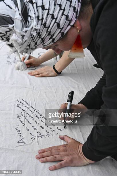 Woman writes on a sheet as hundreds of people, including Jews, gather in front of the Israeli Embassy to collectively mourn the US airman Aaron...