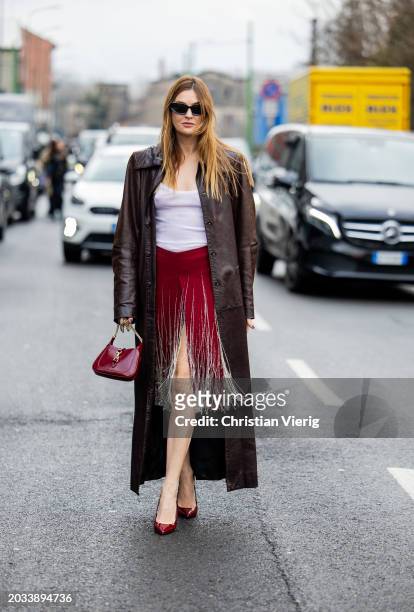 Camille Charriere wears red fringed skirt, white shirt, brown leather coat outside Gucci during the Milan Fashion Week - Womenswear Fall/Winter...