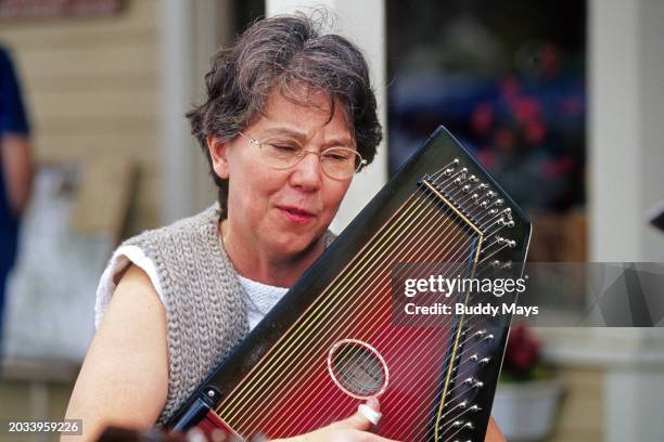 Woman musician plays a zither autoharp in a blue grass band at a blue grass festival in the Appalachian Mountains of northern Georgia, 2010. .