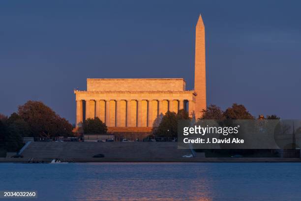 The setting sun casts a warm glow on the Lincoln Memorial and the Washington Monument on February 23 in Washington, DC.