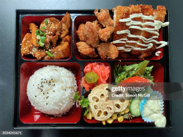 chicken bento box with teriyaki, karaage and katsu chicken portions plus steamed rice, a garden salad, fried lotus root and pickled ginger - plateau à compartiments photos et images de collection