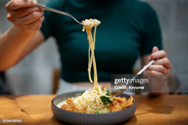 close up shot of a woman eating creamy salted egg pasta - macarrão alimento básico imagens e fotografias de stock