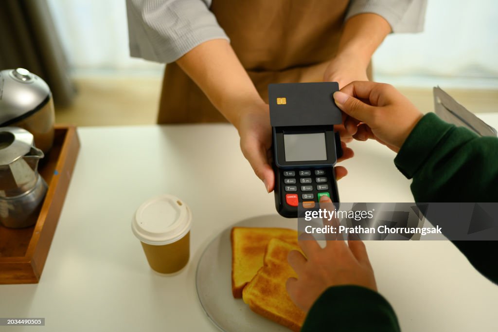 Woman customer hands paying with credit card in cafe. Banking and technology concept
