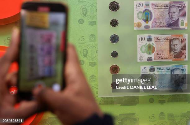 Members of the media film bank notes and coins that feature an image of Britain's King Charles III, during a photocall for 'The Future of Money'...