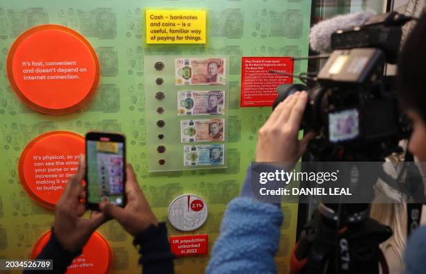 Members of the media film and photograph bank notes and coins that feature an image of Britain's King Charles III, during a photocall for 'The Future...