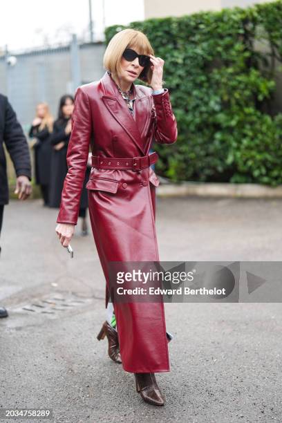 Anna Wintour wears sunglasses, a burgundy leather trench long coat , outside Gucci, during the Milan Fashion Week - Womenswear Fall/Winter 2024-2025...