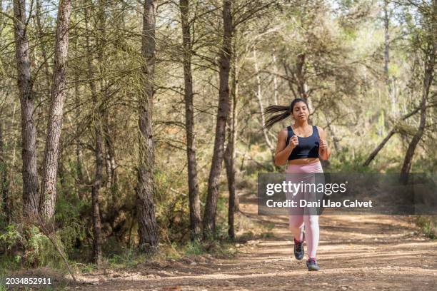 young woman running through forest - kleine scherptediepte stockfoto's en -beelden