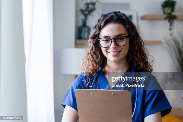 young nurse holding clipboard - doctor scrubs stock pictures, royalty-free photos & images
