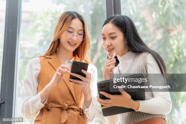 two young gen z women working together on their project using computer tablet at a co-working coffee shop - entrepreneur stockfoto's en -beelden