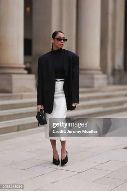 Cherifa Akili seen wearing Saint Laurent black sunglasses, gold earrings, Falke black turtleneck top, Sandro black oversized long blazer jacket,...