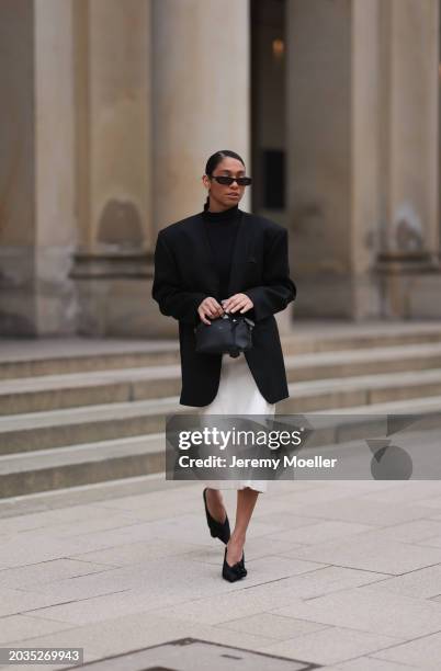 Cherifa Akili seen wearing Saint Laurent black sunglasses, gold earrings, Falke black turtleneck top, Sandro black oversized long blazer jacket,...