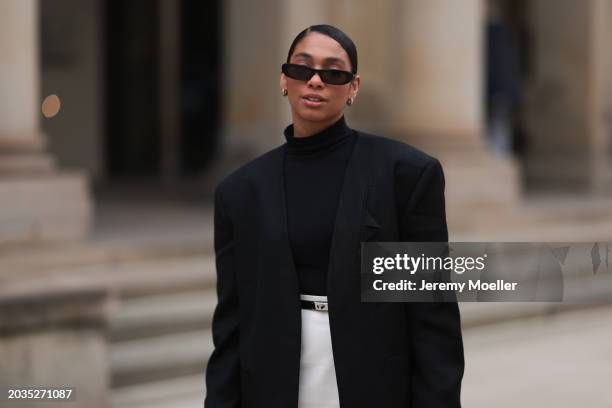 Cherifa Akili seen wearing Saint Laurent black sunglasses, gold earrings, Falke black turtleneck top, Sandro black oversized long blazer jacket,...