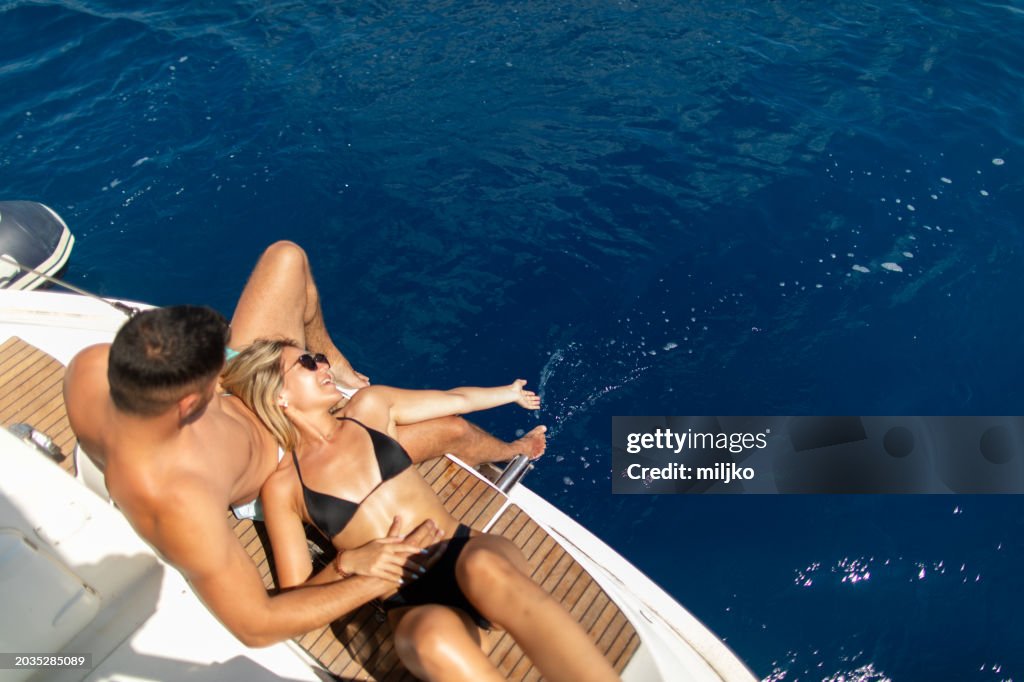 Young couple sitting on a yacht stern while sailing