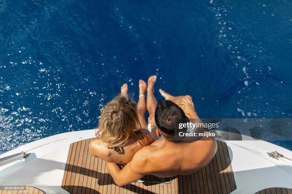 Young couple sitting on a yacht stern while sailing