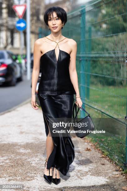 Molly Chiang is seen wearing gold earrings, a black leather Ferragamo bag, black heeled sandals and a black silk x-croos neck tank top with gold...