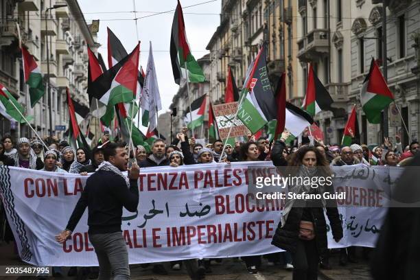 People hold a protest sign and Palestine flags during the Pro-Palestine Demonstration on February 24, 2024 in Milan, Italy. The war between Israel...