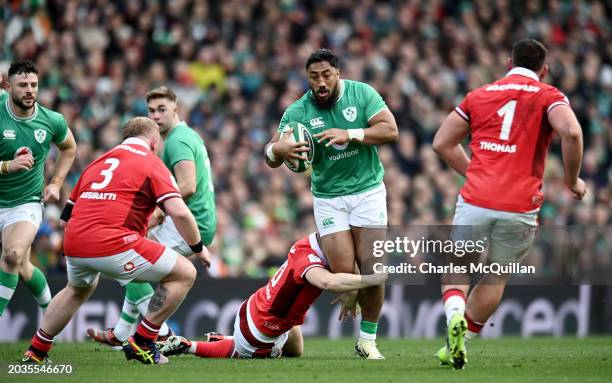 Robbie Henshaw of Ireland runs with the ball whilst under pressure from Sam Costelow of Wales during the Guinness Six Nations 2024 match between...