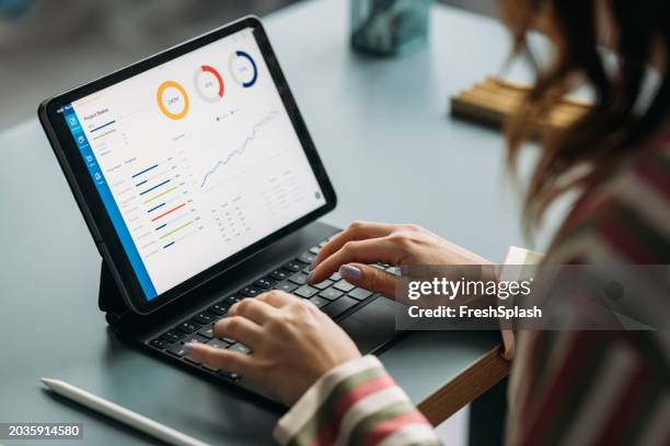 professional woman analyzing data on tablet at work desk - performance management stock pictures, royalty-free photos & images
