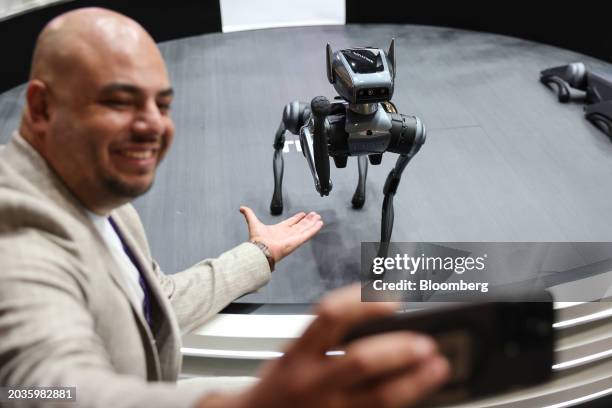 An attendee takes a selfie photograph with a Dynamic 1 robotic dog at the Tecno Mobile Ltd. Booth on day two of the Mobile World Congress at the Fira...