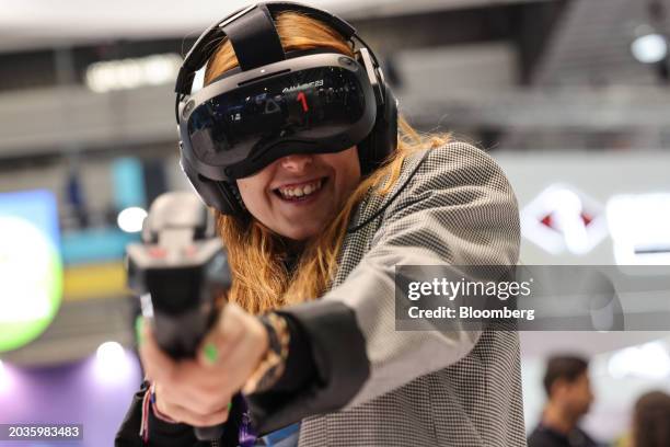 An attendee wears a VIVE Focus virtual reality headset to play a shooting game at the HTC Corp. Booth on day two of the Mobile World Congress at the...