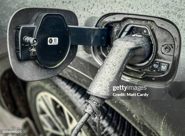 Electric car is charged by a wall charger in a city centre car park, on February 25, 2024 in Bath, England. The government's commitment to reducing...