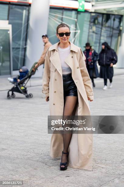 Nataly Osmann wears beige trench coat, black shorts, white shirt, tights, heeled sandals outside Ermanno Scervino during the Milan Fashion Week -...