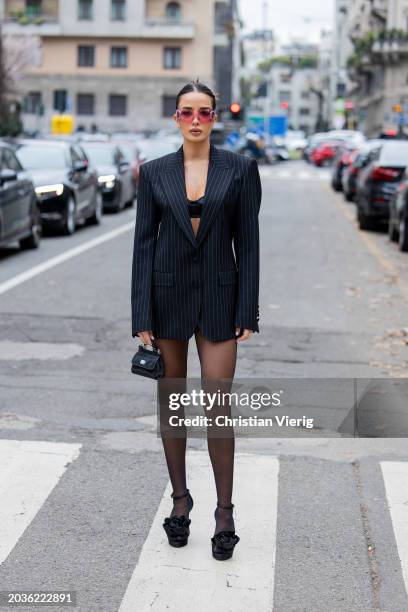 Guest wears black white striped blazer, tights, mini bag, sunglasses outside Dolce & Gabbana during the Milan Fashion Week - Womenswear Fall/Winter...