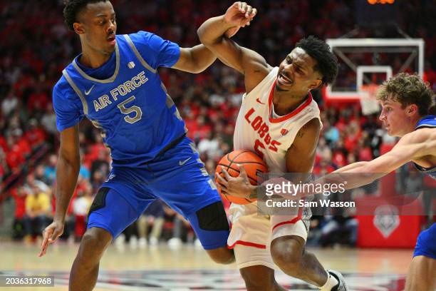 Jamal Mashburn Jr. #5 of the New Mexico Lobos drives to the basket against Ethan Taylor and Kellan Boylan of the Air Force Falcons during the second...