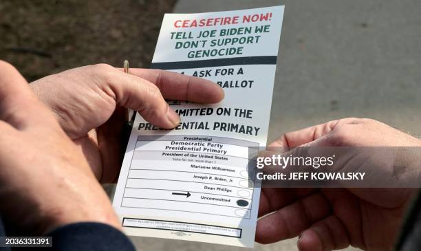 Volunteer shows a person how to vote uncommitted, instead of for US President Joe Biden, outside of Maples School in Dearborn, Michigan on February...