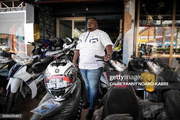 Henri Joël Kaboré, manager of J-Motors poses in front of his store in Ouagadougou, on February 22, 2024 where he sells motorcycles and helmets. His...