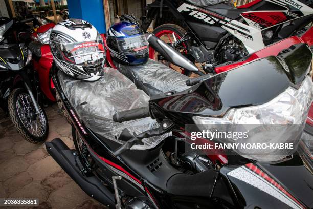 Helmets and motorcycles are displayed for sale at the J-Motors showroom in Ouagadougou, on February 22, 2024. His moped speeds through the dusty...