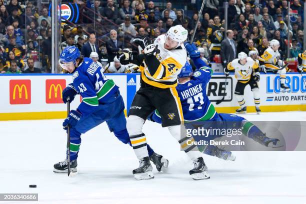 Quinn Hughes and Filip Hronek of the Vancouver Canucks check Jansen Harkins of the Pittsburgh Penguins during the second period at Rogers Arena on...