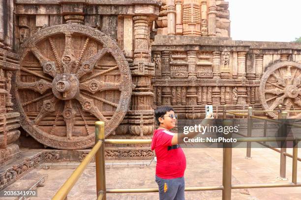 Child is taking a selfie in front of a carved stone wheel at the Konark Sun Temple in Konark, Odisha, on February 24, 2024. The Konark Sun Temple, a...