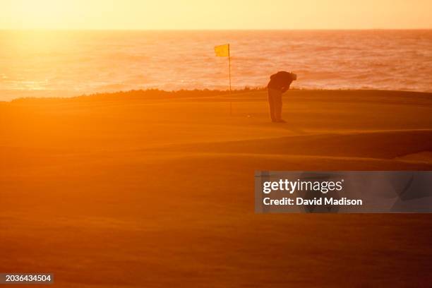 General view at sunset as a golfer putts on the 14th green of the Dunes Course at the Monterey Peninsula Country Club in November 1987 in Pebble...