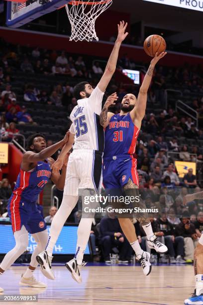 Evan Fournier of the Detroit Pistons dives to the basket against Goga Bitadze of the Orlando Magic during the first half at Little Caesars Arena on...