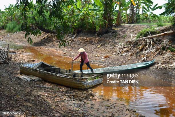 This photo taken on February 23, 2024 shows a farmer crossing over an almost completely dried up canal in southern Vietnam's Ca Mau province, amid a...