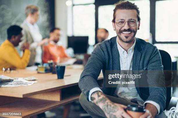 focus on a smiling young businessman during a meeting - coworking imagens e fotografias de stock