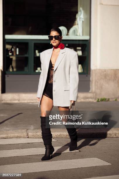 Gili Biegun wears long black boots, a black mini dress, a grey oversized blazer, a red rose or flower neck accessory and a Valentino bag outside...