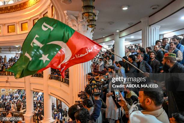 Supporters of jailed former prime minister Imran Khan's Pakistan Tehreek-e-Insaf party wave the party's flag during an oath taking ceremony of PTI's...