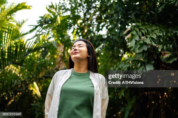 donna contemplativa in mezzo al fogliame tropicale - solo donne mature foto e immagini stock